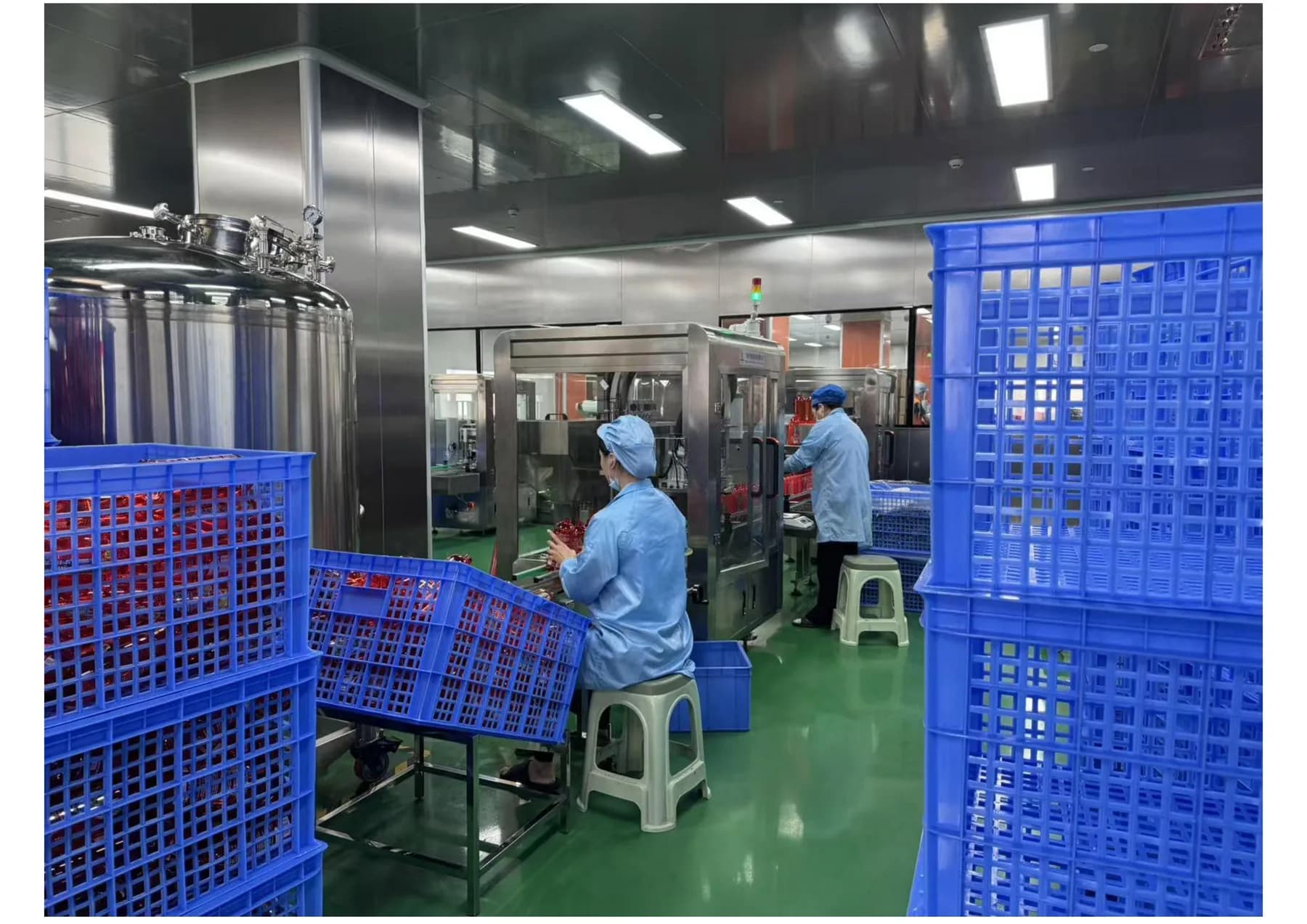 Operators working beside cosmetics filling equipment in a King Metis clean production workshop
